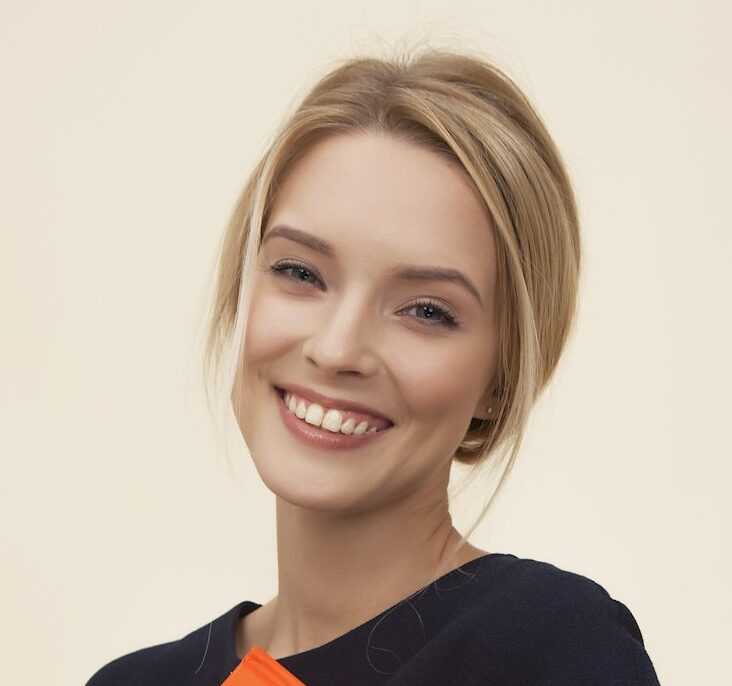smiling woman standing while holding orange folder